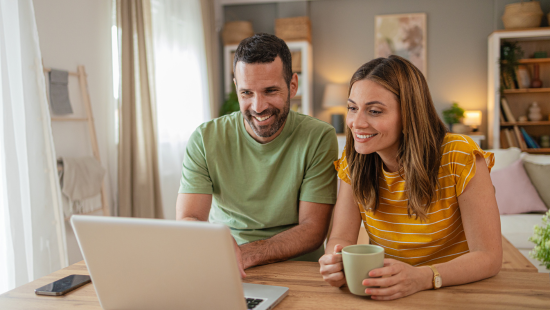 man and woman sitting at table looking at computer